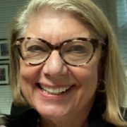 A photo of a smiling woman with blonde hair with brown tortoise shell glasses.